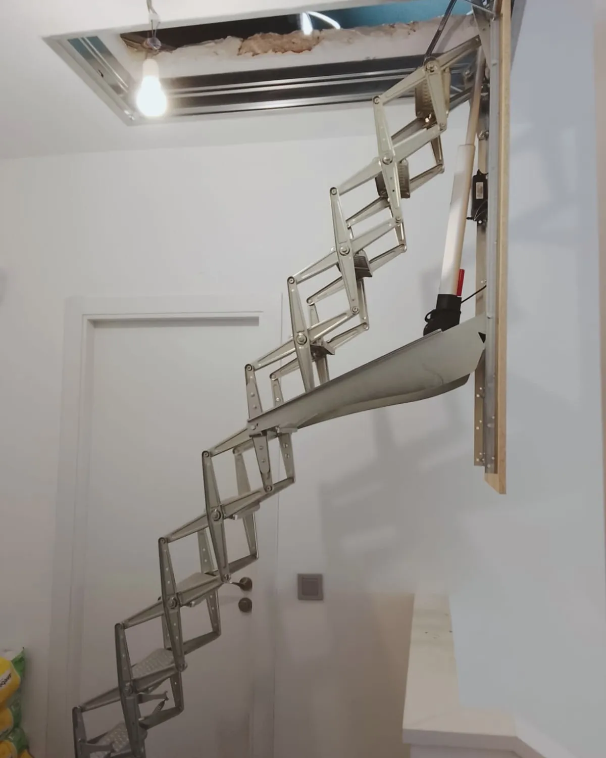 Escalera escamoteable pantográfica de aluminio desplegada desde el techo