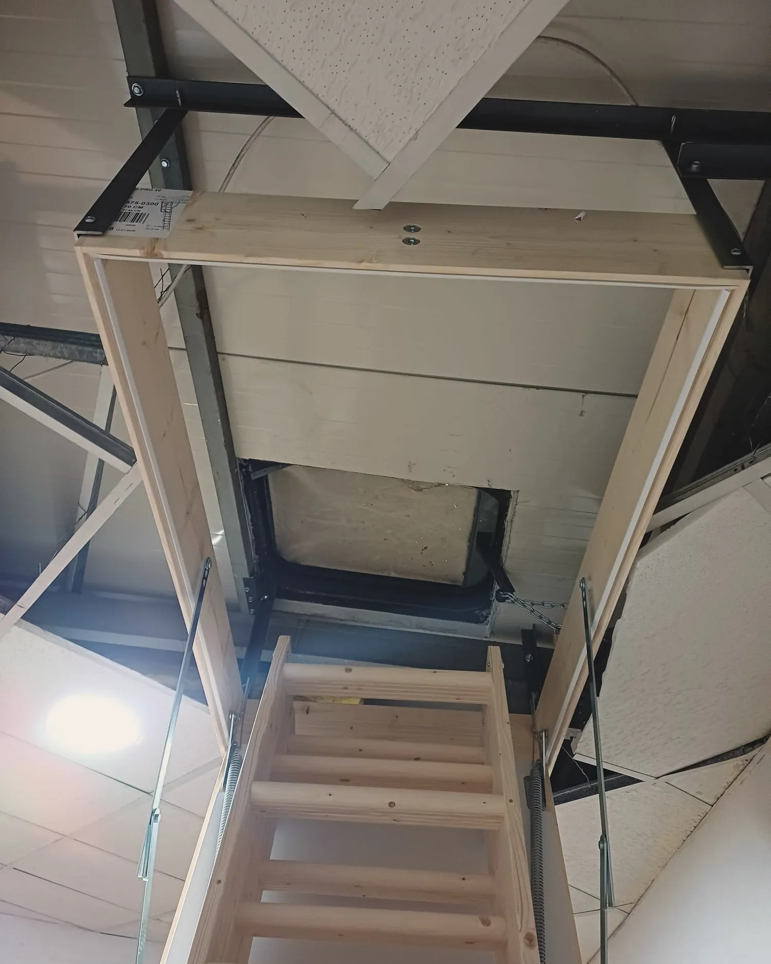 Escalera escamoteable de madera desplegada bajo el hueco del techo