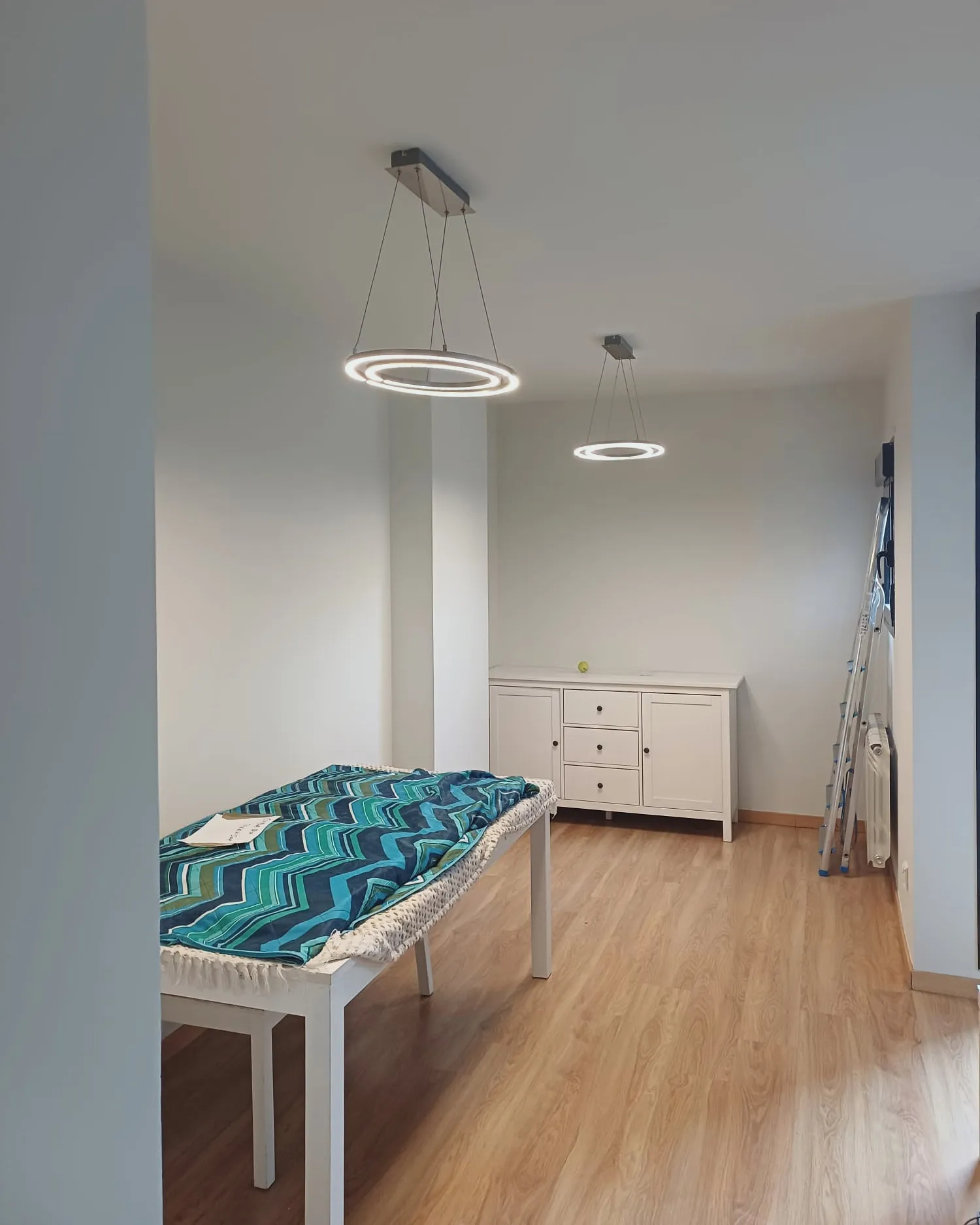 Salón comedor terminado con lámparas circulares y paredes en blanco roto