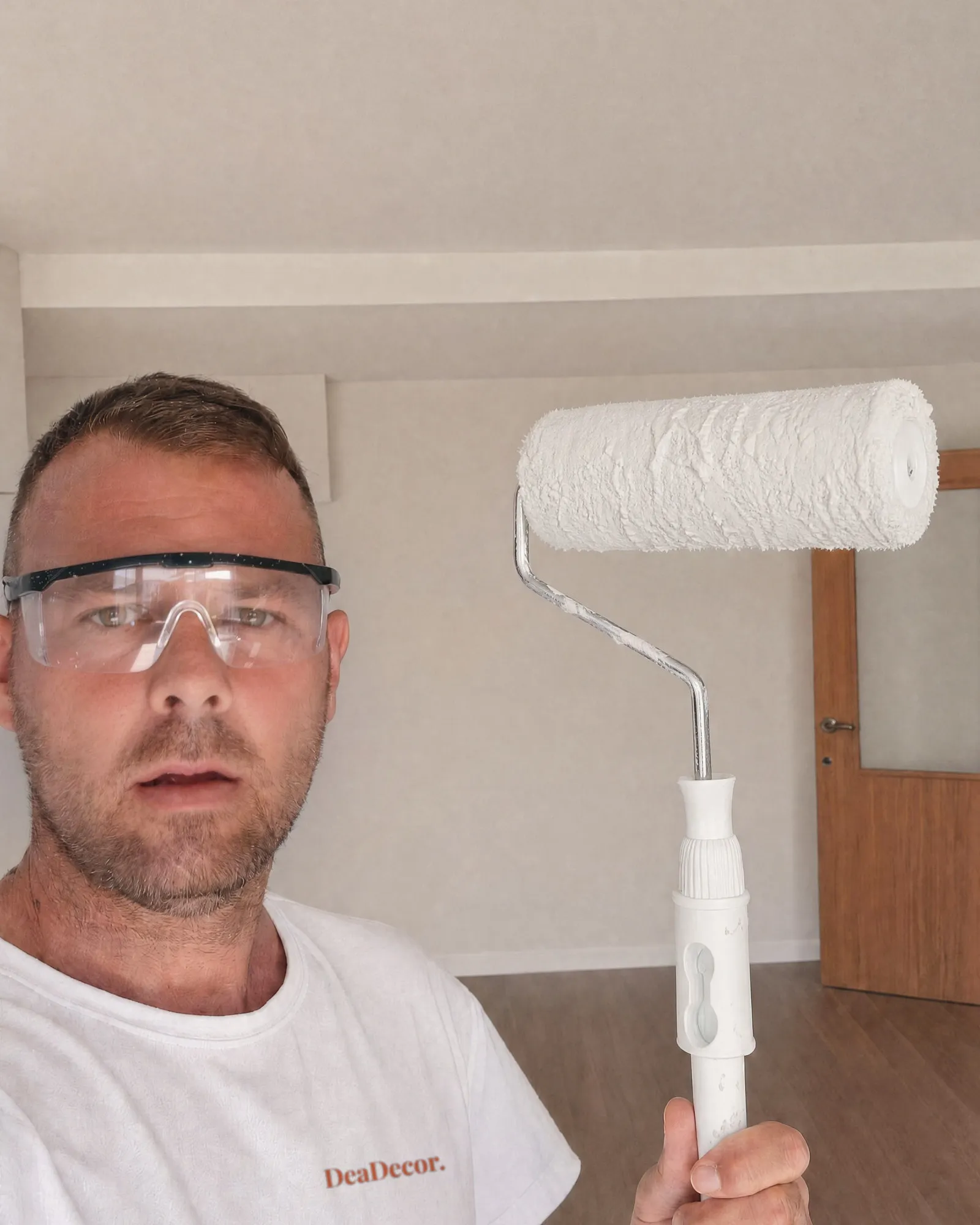 Adrián, de DeaDecor, con gafas de seguridad y un rodillo cargado de pintura.